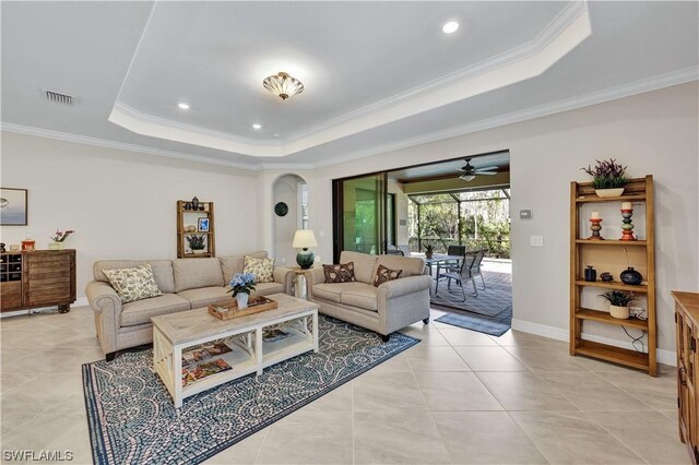 tiled living room with a raised ceiling, ceiling fan, and ornamental molding