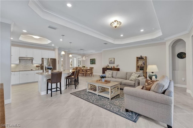 tiled living room with a tray ceiling and ornamental molding