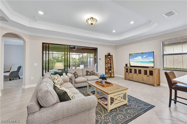 living room featuring light tile patterned floors, a raised ceiling, ceiling fan, and crown molding