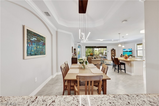 dining room with light tile patterned floors, a tray ceiling, and crown molding