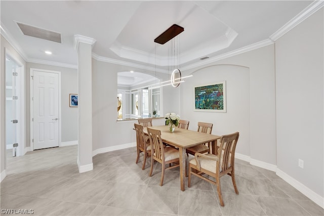 dining room with light tile patterned floors, a tray ceiling, and ornamental molding