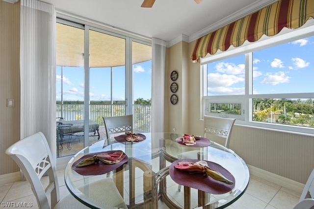 tiled dining space featuring ceiling fan, crown molding, and a water view