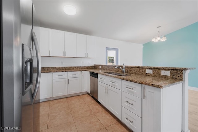 kitchen with kitchen peninsula, hanging light fixtures, white cabinets, and stainless steel appliances