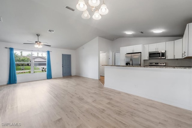 kitchen with white cabinets, dark stone counters, lofted ceiling, and appliances with stainless steel finishes