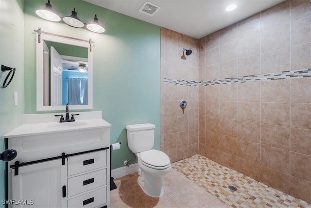 bathroom with tile patterned floors, a tile shower, vanity, ceiling fan, and toilet