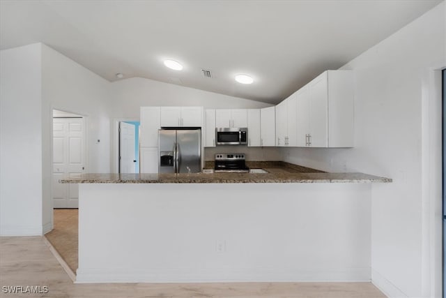 kitchen featuring kitchen peninsula, stainless steel appliances, vaulted ceiling, and white cabinets