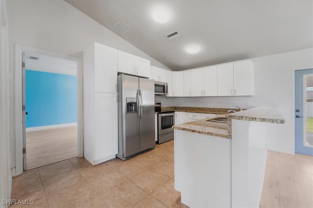 kitchen featuring lofted ceiling, white cabinets, sink, appliances with stainless steel finishes, and kitchen peninsula