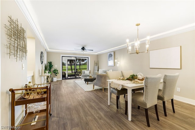 dining room with dark wood-type flooring, crown molding, and ceiling fan with notable chandelier