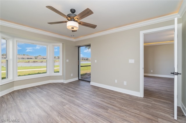 empty room featuring ornamental molding, a healthy amount of sunlight, ceiling fan, and dark wood-type flooring