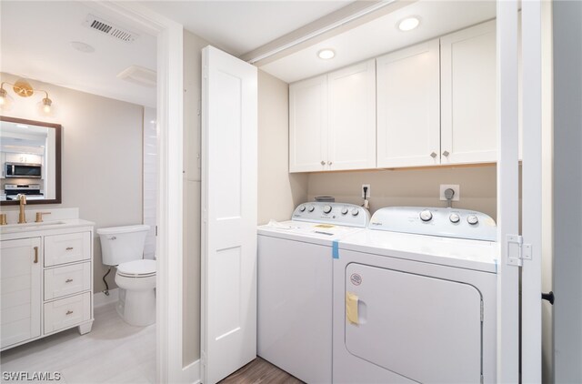 washroom with cabinets, hookup for an electric dryer, washer and dryer, and sink