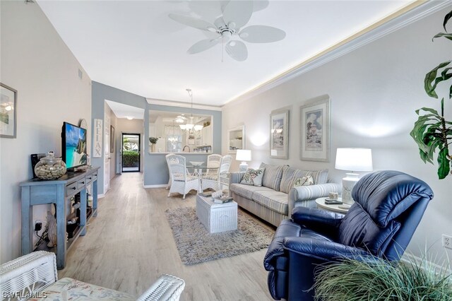 living room with ornamental molding, ceiling fan with notable chandelier, and light hardwood / wood-style flooring