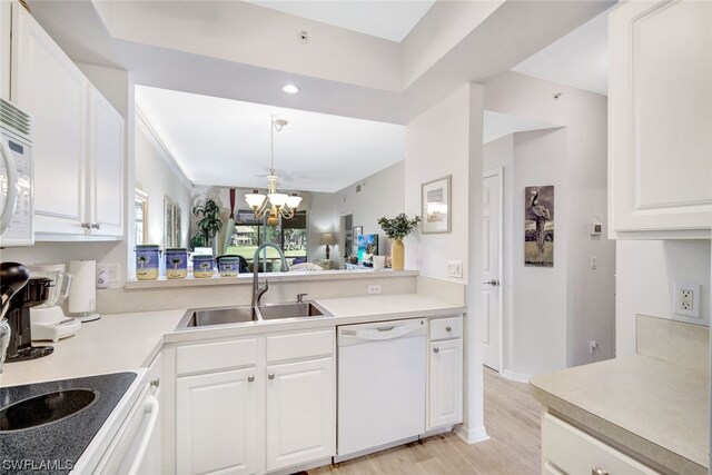 kitchen with white appliances, a notable chandelier, white cabinets, and sink