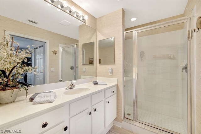 bathroom with a shower with door and vanity with extensive cabinet space