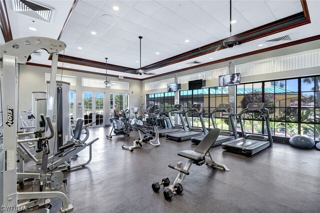 workout area featuring a tray ceiling, ornamental molding, and french doors