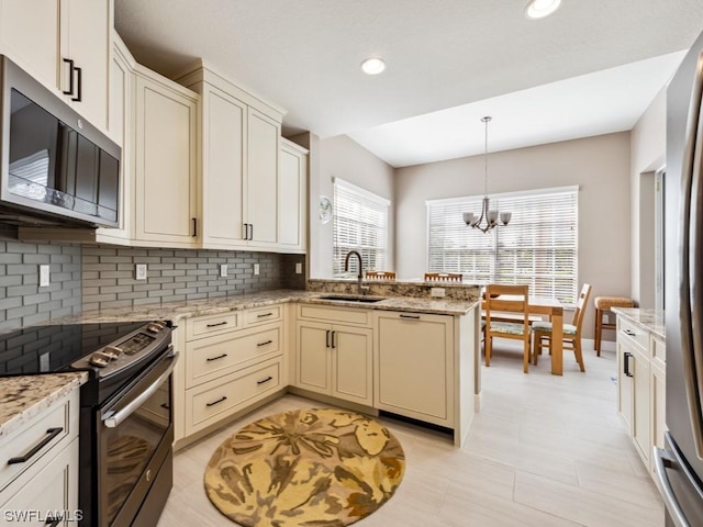 kitchen with decorative light fixtures, sink, light stone countertops, and stainless steel appliances