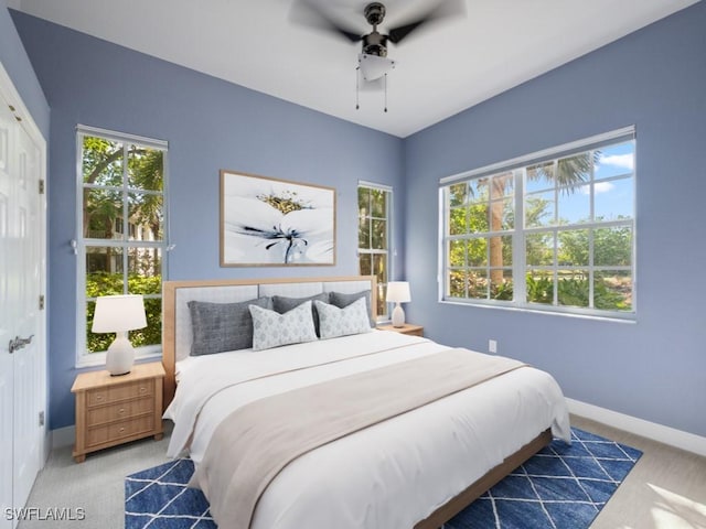 carpeted bedroom featuring ceiling fan, a closet, and multiple windows