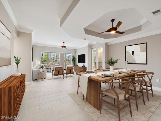 dining room with a tray ceiling, crown molding, and ceiling fan