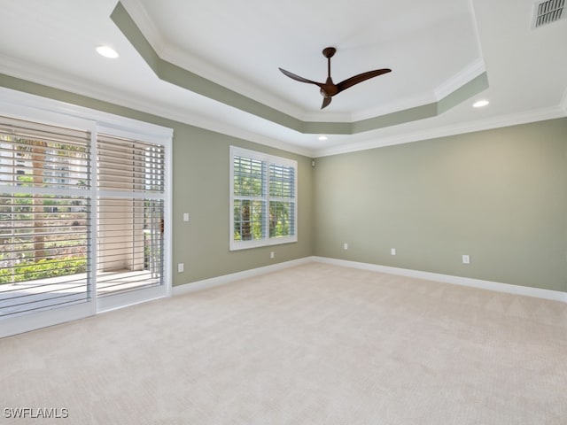 spare room with light carpet, a tray ceiling, ceiling fan, and crown molding