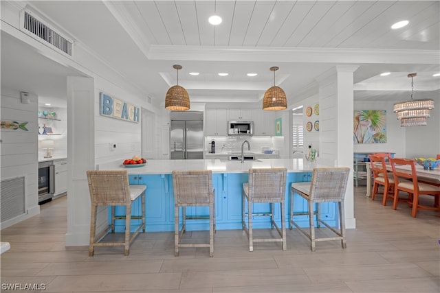 kitchen featuring hanging light fixtures, a kitchen breakfast bar, appliances with stainless steel finishes, light hardwood / wood-style floors, and white cabinets