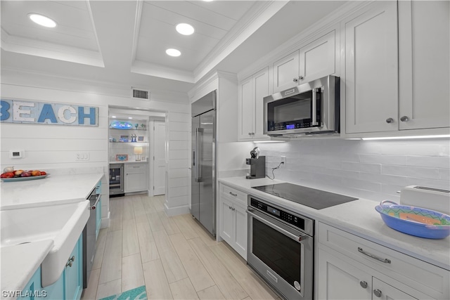 kitchen featuring white cabinets, appliances with stainless steel finishes, wine cooler, tasteful backsplash, and light wood-type flooring