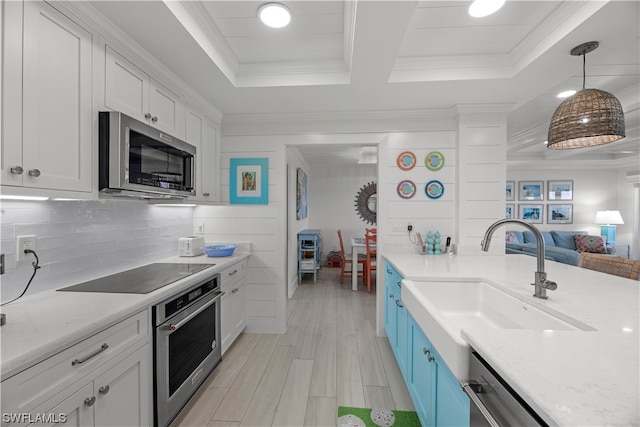 kitchen featuring light stone countertops, decorative light fixtures, appliances with stainless steel finishes, sink, and white cabinets