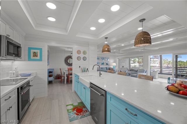 kitchen featuring appliances with stainless steel finishes, white cabinets, hanging light fixtures, a raised ceiling, and sink