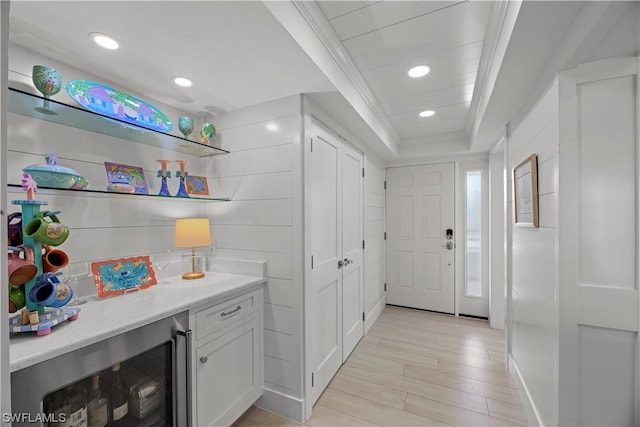 interior space with vanity, beverage cooler, a tray ceiling, and hardwood / wood-style flooring