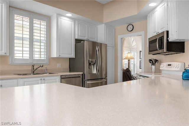 kitchen featuring appliances with stainless steel finishes, white cabinets, a sink, and light countertops