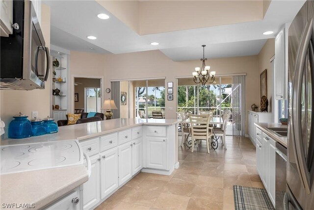 kitchen with white cabinetry, stainless steel appliances, a notable chandelier, kitchen peninsula, and decorative light fixtures