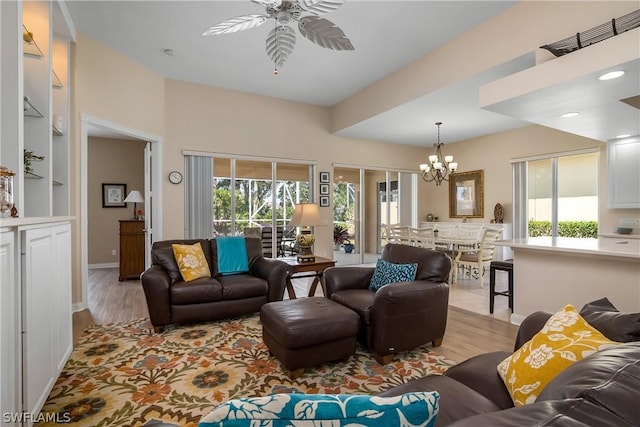 living area featuring a healthy amount of sunlight, light wood-style flooring, and ceiling fan with notable chandelier