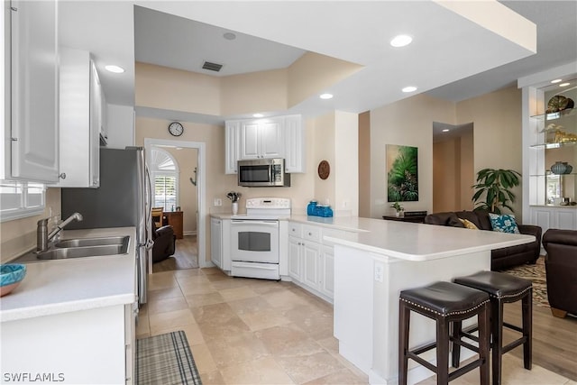 kitchen featuring white cabinetry, sink, a kitchen breakfast bar, kitchen peninsula, and electric stove