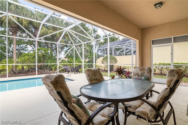 exterior space featuring outdoor dining area, glass enclosure, and a patio