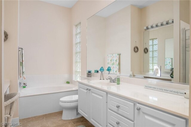 bathroom featuring tile patterned flooring, vanity, toilet, and a tub