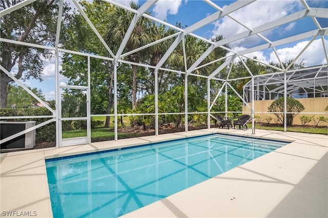 view of pool featuring glass enclosure and a patio area