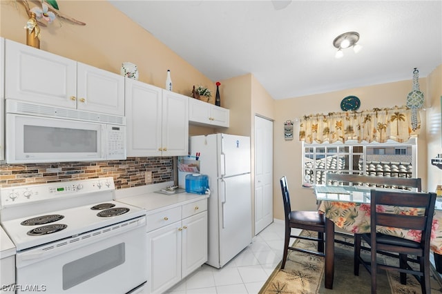 kitchen with white appliances, light tile floors, backsplash, vaulted ceiling, and white cabinetry