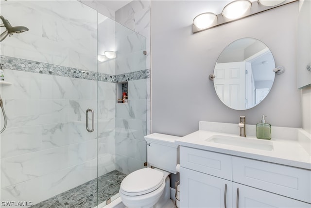 bathroom with toilet, a shower with shower door, and vanity with extensive cabinet space