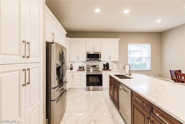 kitchen with sink, light tile floors, white cabinets, appliances with stainless steel finishes, and backsplash