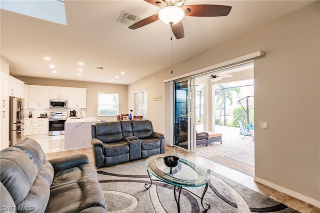 living room with ceiling fan, light tile floors, and sink