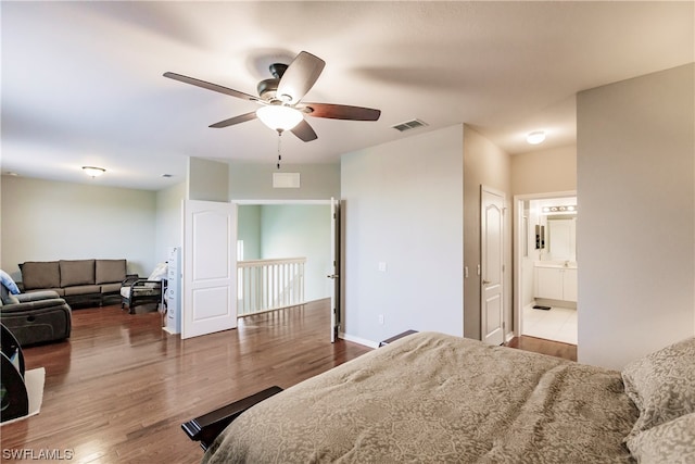 bedroom featuring ceiling fan, ensuite bath, and dark wood-type flooring