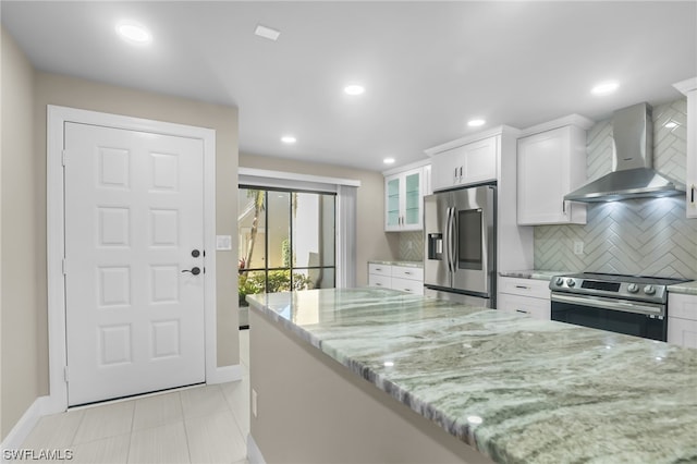 kitchen featuring light stone counters, white cabinets, appliances with stainless steel finishes, backsplash, and wall chimney exhaust hood