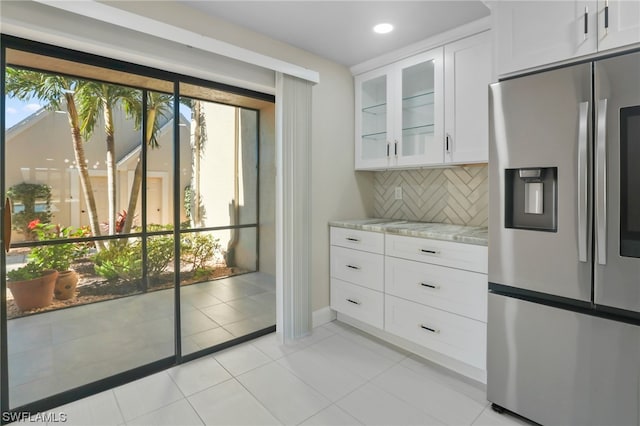 kitchen featuring tasteful backsplash, stainless steel fridge, white cabinets, and light tile floors