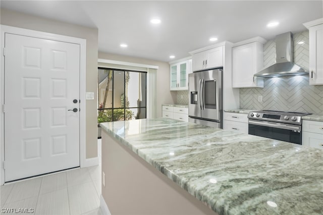 kitchen with white cabinets, backsplash, stainless steel appliances, and wall chimney exhaust hood