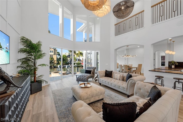 living room featuring light hardwood / wood-style flooring, an inviting chandelier, and a high ceiling