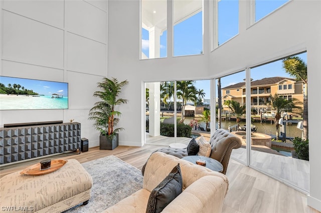 living room featuring a high ceiling, a water view, and light wood-type flooring