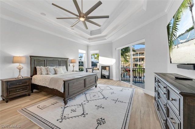 bedroom with access to exterior, ceiling fan, ornamental molding, a tray ceiling, and light wood-type flooring