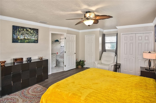 bedroom featuring dark wood-type flooring, ensuite bathroom, ceiling fan, and multiple closets