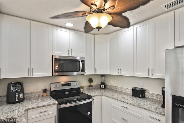 kitchen with light stone countertops, white cabinets, and stainless steel appliances