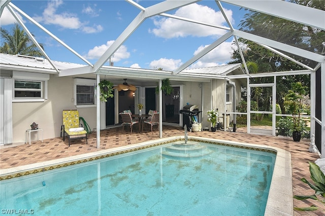 view of pool with glass enclosure, area for grilling, a patio area, and ceiling fan