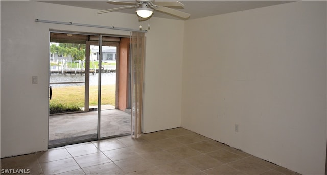 tiled empty room featuring a water view and ceiling fan