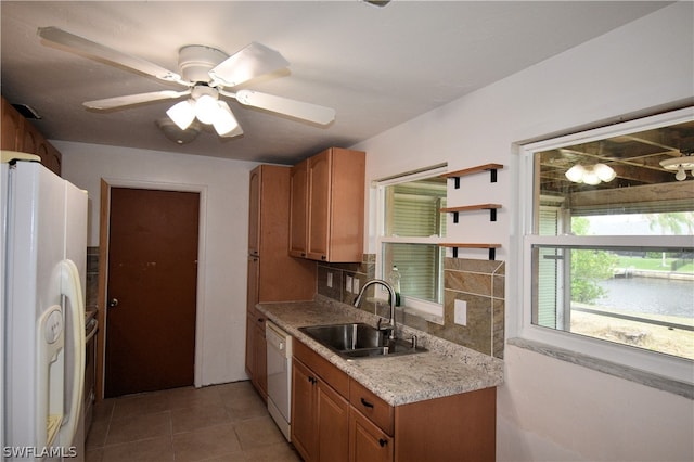 kitchen with sink, light tile patterned floors, a water view, white appliances, and ceiling fan